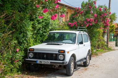 Skiathos, Yunanistan. 06 26 23. Lada Niva klasiği beyaz 4x4, renkli çiçekli arka planda park edilmiş. Arabanın önüne odaklan..