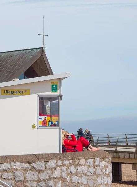 Exmouth, Devon, İngiltere. 05 06 23. Bir cankurtaran Devon 'daki Exmouth plajını izliyor. Net görebilmek için gözlerini güneşten koruyor. Cankurtarana odaklan. Deniz güvenliği görüntüsü. Boşluğu kopyala.