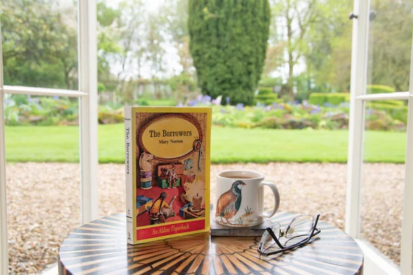 Ideford, Devon, İngiltere. 15 Nisan 2023. The Borrowers, yazan Mary Norton. Resim yumuşak odaklı bir bahçe arka planına göre ayarlanmış. Ön kapağa odaklan. Klasik kitap.