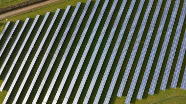 Güneş paneli çiftlik havası görüntüsü. Güneş panelleriyle dolu bir alan yeşil çimenli bir alanda oturup temiz sıfır karbon enerjisi üretiyor. Güneş enerjisi üretimi. sürdürülebilir iklim görselleri