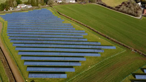 Solar panel farm aerial view with copy space. A fields full of solar panels sits in a green grassy field producing clean zero carbon energy. Solar energy production. sustainable climate visuals