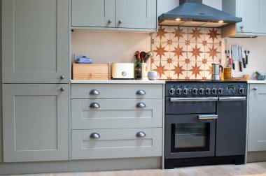 Diptford, Devon, İngiltere. 2 Şubat 2023. Rangemaster fırın fırını, kapüşonlu ve her iki tarafında da aynı dolaplar var. Modern ama taşra mutfağında yemek hazırlama. Boşluğu kopyala.