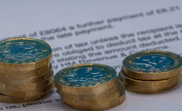 Pound coins stacked on a letter quoting financial information. Good editorial image for finance and investment. Sharp selective focus on the leading edge of the coins with soft focus beyond.
