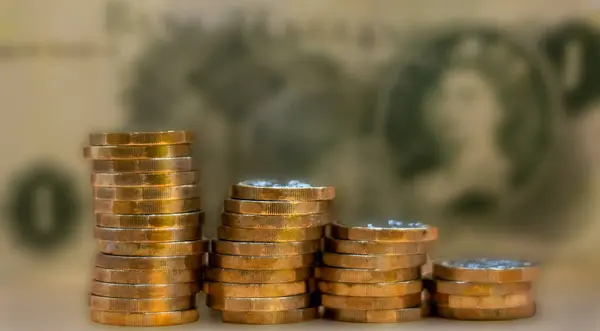 Stacks of pound coins in selective focus against an old pound note in very soft focus. Financial and economic image depicting old and new currency.