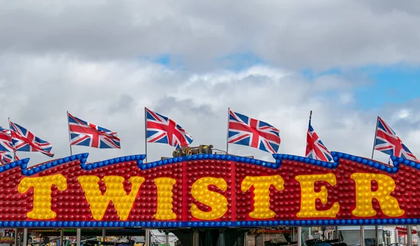 Paignton, Devon, İngiltere. 23 Ağustos 2022. Paignton panayır sendikası bayrakları Twister 'ın üstünde dalgalanıyor. Paignton 'daki renkli Twister panayırında birkaç sendika bayrağı dalgalanıyor. 