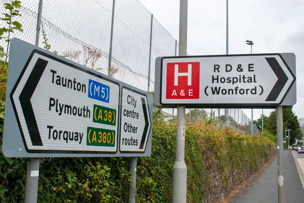 Exeter, Devon, İngiltere. 18 Ağustos 2022. Exeter 'deki Royal Devon ve Exeter hastanesinin hastane tabelası. Acil durum işareti. Yanındaki büyük tabelada Taunton, Plymouth, Torquay yazıyordu. Acil Durum NHS