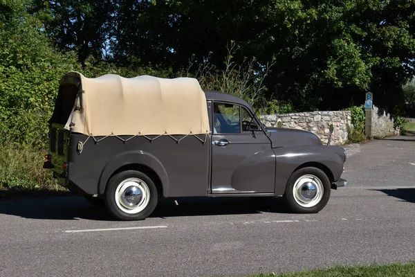 Powderham, Devon, İngiltere. 9 Temmuz 2022. Güneşli bir öğleden sonra, solaryum bezi çatısı olan klasik bir Morris Minor pikap. Beyaz çelik tekerlekler bu nadir tarihi aracı gösteriyor..