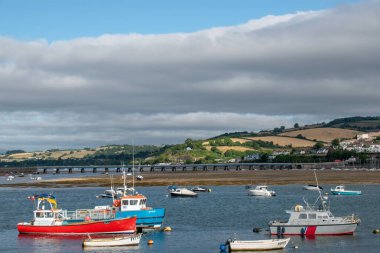 Teignmouth, Devon, İngiltere. 8 Temmuz 2022. Sabahın erken saatlerinde Teignmouth 'tan alınan Shaldon Köprüsü manzarası. Renkli balıkçı tekneleri köprüyü geçen haliçleri kararıyor. 