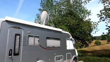 Exeter, İngiltere. 07-14-22. Karavanın uydu anteni düzgünce çatıdaki düz bir konuma, uydu alıcısı olan gümüş bir karavana geri çekiliyor..