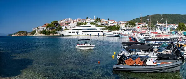 stock image Skiathos, Greece. 06-20-24. Skiathos wide angle panorama showing the picturesque harbour with a super yacht moored before Plakes. 