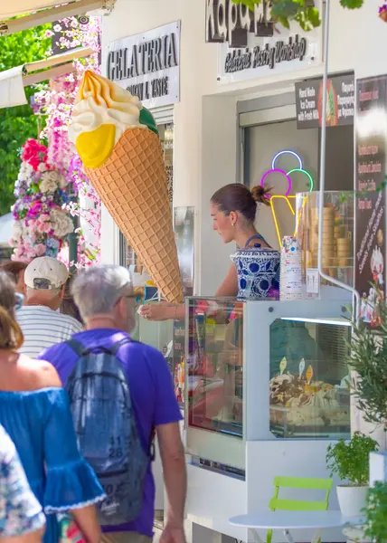 Skiathos, Yunanistan. 06-29-24. Skiathos Papadiamanti caddesinde turistlere dondurma servisi yapan bir bayan var. Canlı, renkli bir görüntü.. 