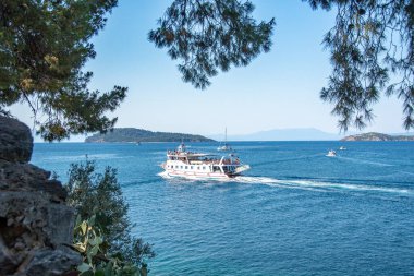 Skiathos, Yunanistan. 06-24-24. Soluk mavi sularda seyir eden bir yolcu teknesiyle kayaklar. Sporades adalarının bir parçası. Yunan bayramı ve tatil filmi.