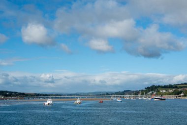 Teignmouth, Devon, İngiltere. 09-12-24. Shaldon Köprüsü ve haliçleri Teignmouth 'tan görüldüğü gibi. Tekneler ve mavi gökyüzü. 