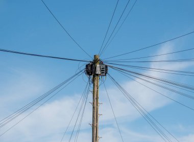 Telgraf direğindeki kablolar ve kablolar mavi gökyüzüne karşı. Telefon ve iletişim görüntüsü. Bilim ve teknoloji kavramı.