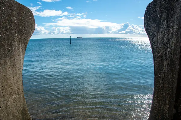 stock image Curved concrete sea wall with concrete steps in foreground. Civil engineering and flood prevention through reinforced coastal sea defenses.