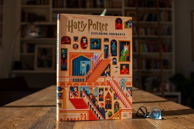 Torbryan, Devon, İngiltere. 10-26-24. Harry Potter Hogwarts 'ı keşfediyor, kitap. Koyu bir kitaplığın arka planına karşı renkli bir kitap kapağı.