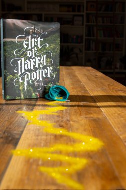 Torbryan, Devon, İngiltere. 10-26-24. Harry Potter sanatı. Koyu bir kitaplığın arka planına karşı renkli bir kitap kapağı.