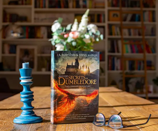 Torbryan, Devon, İngiltere. 10-26-24. J K Rowling 'in Dumbledore' un Sırları. Harry Potter Renkli Kitap kapağıyla karanlık bir kitaplığın arka planı karşı karşıya.