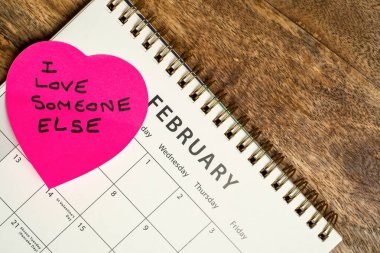 Valentines day calendar with the message I love someone else, on a pink heart shaped post it note. clipart