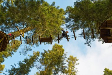 Warminster, Wiltshire, İngiltere. 01-23-25. Merkez parklar Havadan Ağaç Yürüyüşü görüntüsü askıya alınmış kütük yürüyüşü yapan birine bakıyor. Macera ve heyecan. Tatil ve kısa bir tatil aile eğlencesi.