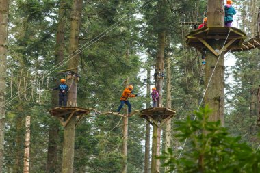 Warminster, Wiltshire, İngiltere. 01-23-25. Merkez parklar Havadan Ağaç Yürüyüşü görüntüsü askıya alınmış bir kütük yürüyüşünü geçen kişiye bakıyor. Macera ve heyecan. Tatil ve kısa bir tatil aile eğlencesi.
