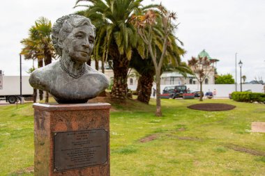 Torquay, Devon, uk. 06-11-25. Agatha Christie 'nin Torquay, Devon' daki büstü. Torquay 'ın ünlü palmiye ağaçları arka planda oturur..