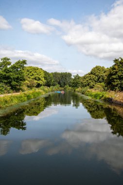 Exeter kanalı, suda güçlü ve canlı yansımalarla dolu güzel bir günde. İnsanlar su sporlarını uzaktan takip ederken görülebilir. Güneybatı İngiltere turizm ve eğlence. İyi kopyalama alanı. 