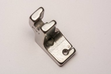 Dikiş makinesinin ayağını beyaz arkaplanda izole ettim. Dikiş makineleri, dikiş ekipmanları için yedek parçalar..