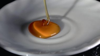 Bal yukarıdan beyaz tabağa damlıyor.