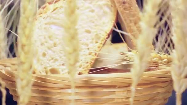 スライスされたパンとその周りの小麦の耳のウィッカーバスケット — ストック動画