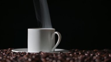 Kavrulmuş kahve çekirdeği ve sıcak kahve fincanı..