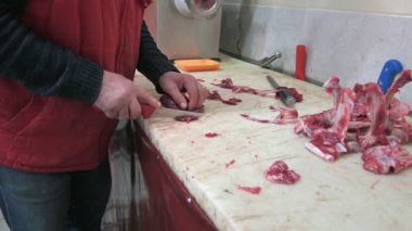 Tahta üzerinde bir dana eti. Şef ağır çekimde çiğ eti bıçakla kesiyor.