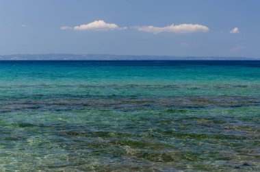 Mavi deniz ve bulutlu gök mavisi. Açık sarı kum. Doku, arkaplan, kopyalama alanı