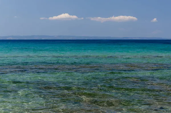 Mavi deniz ve bulutlu gök mavisi. Açık sarı kum. Doku, arkaplan, kopyalama alanı