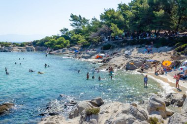 Mega Portokali Plajı 08-05-2023 Yunanistan, Halkidiki, Sithonia. Plaj şemsiyeleri, beyaz kayaları, masmavi gökyüzü olan bir sürü insan.