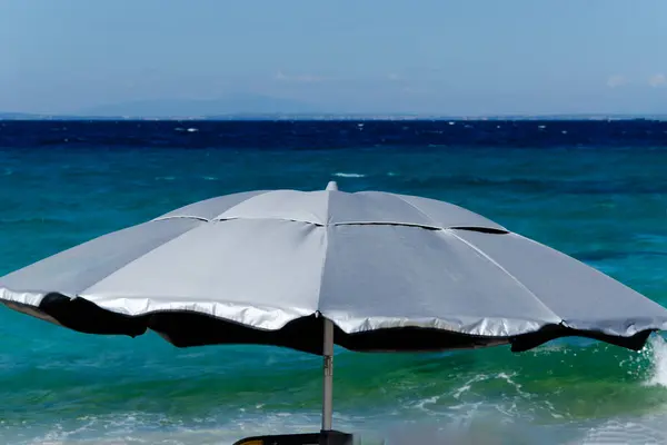 silver beach umbrella against sea and wind. Close-up, background, copy space, horizon and sky