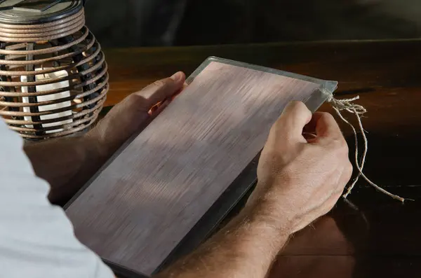 close-up of restaurant menu in hands of a man. On left is candlestick with candle. background is brown.