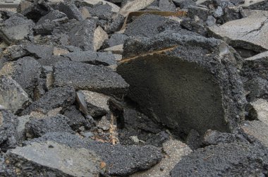 Yakından bakıldığında, muhtemelen yıkılmış tramvay rayları veya bir yoldan kaynaklanan büyük bir asfalt yığını ve daha küçük enkaz parçaları görülüyor. Koyu gri parçaların kabataslak dokuları ve çeşitli boyutları baskın.