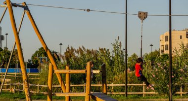 Çocuklar eğlence parkında teleferik hattıyla eğleniyor.