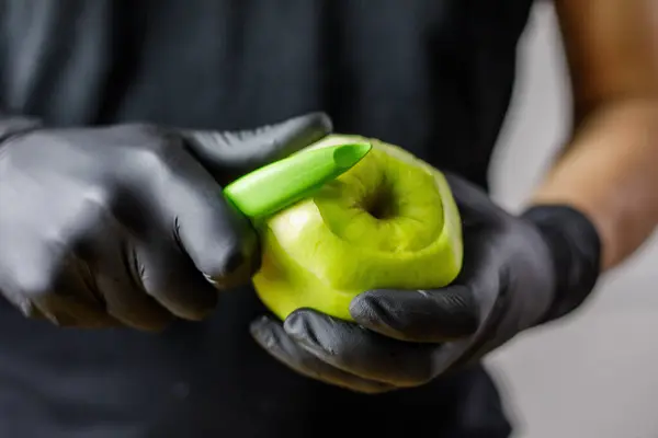 Siyah eldivenli biri yeşil elma soyacağı ile elma soyuyordu. Yüksek kalite fotoğraf