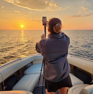 Güzel bir gündoğumu ya da gün batımı manzarası telefonuyla fotoğraf çeken bir kadın.