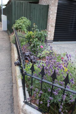 Çeşitli türde çiçekleri ve küçük metal çitleri olan tuğla çiçek tarhı.