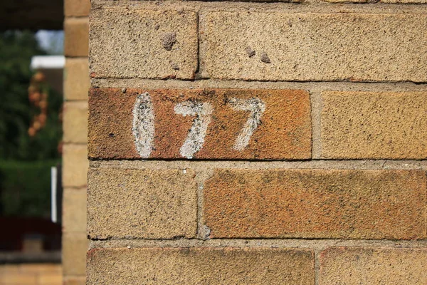 Numbers 177 painted onto a brick house, up close picture