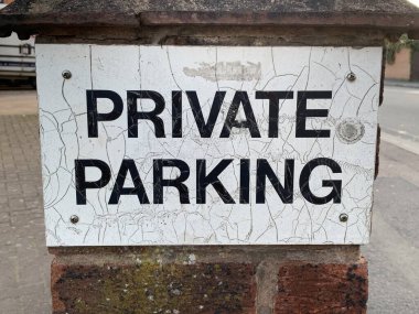 Eski yıpranmış özel park yeri tabelasının yakın bir resmi.