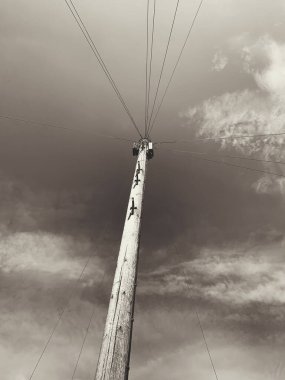 Telefon kabloları gökyüzü ve bulutlu bir iletişim telgraf direğinin tek renkli resmi.