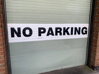 İngiltere 'nin kırsal bir sokağında çekilen gri metal bir garaj kapısına park levhası yapıştırılmamış.