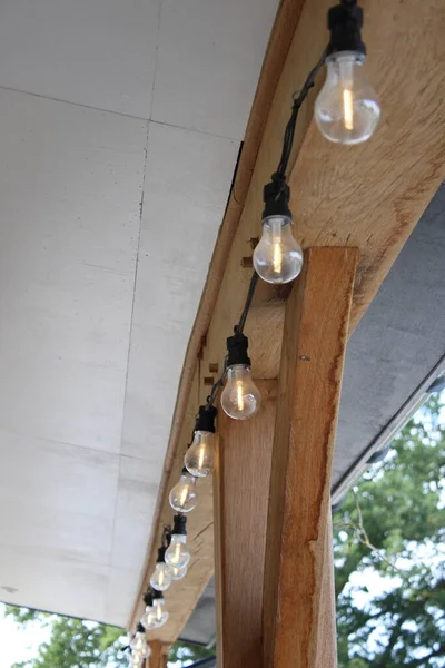 A set of outdoor string LED lights under a wooden frame