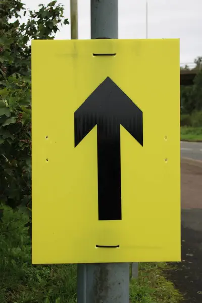 Yellow sign with Black arrow used for marathon runners to indicate route direction to runners