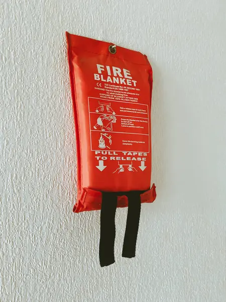 A red Kitchen fire blanket hanging on a white wall
