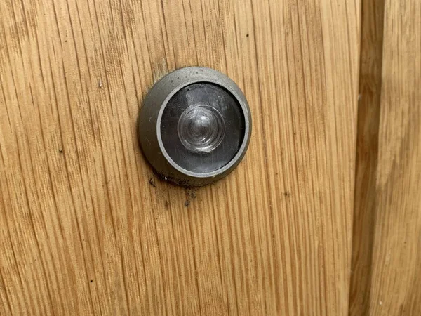 Close up picture of a door peep hole attached to a wooden door
